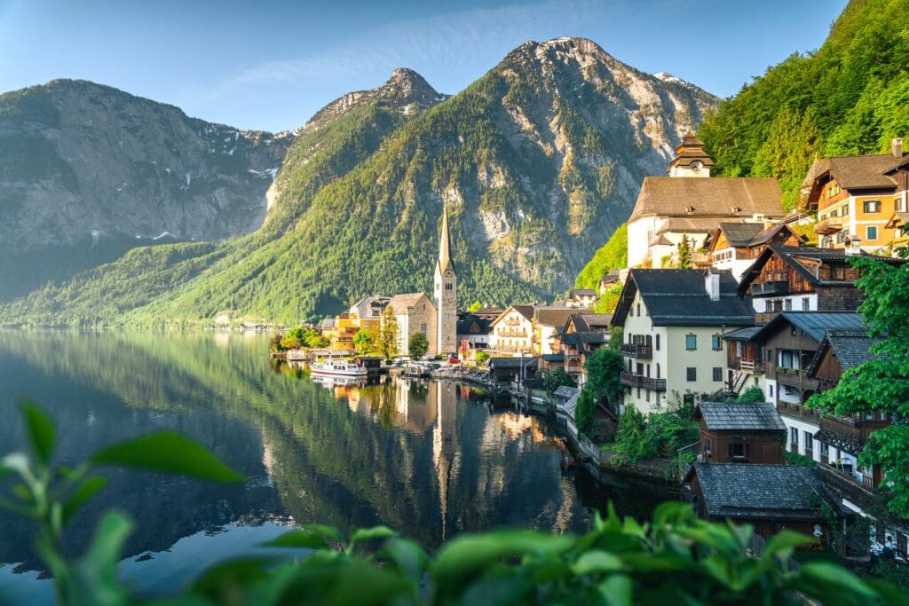 The charming village of Hallstatt, Austria reflected in a glassy alpine lake, surrounded by dramatic mountain peaks — a classic European river cruise destination.